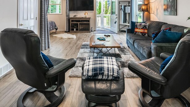 A modern living room with a sofa, two leather chairs, a coffee table, and a TV. - Nesting Ravens B@B .Large ,  suite on Private Acreage, Safe and enjoyable stay! (Nanaimo)