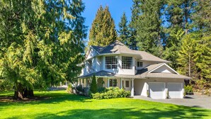 A two-story house with a large front porch, garage, and a well-maintained lawn. - Nesting Ravens B@B .Large ,  suite on Private Acreage, Safe and enjoyable stay! (Nanaimo)