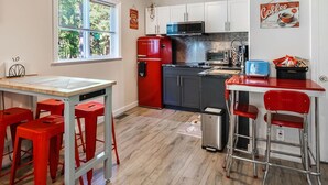 A compact kitchen with a red refrigerator, a microwave, and a coffee machine. There are two red bar stools and a small table with a white tablecloth. - Nesting Ravens B@B .Large ,  suite on Private Acreage, Safe and enjoyable stay! (Nanaimo)