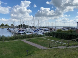 A marina with boats docked, a grassy area, and a clear sky.