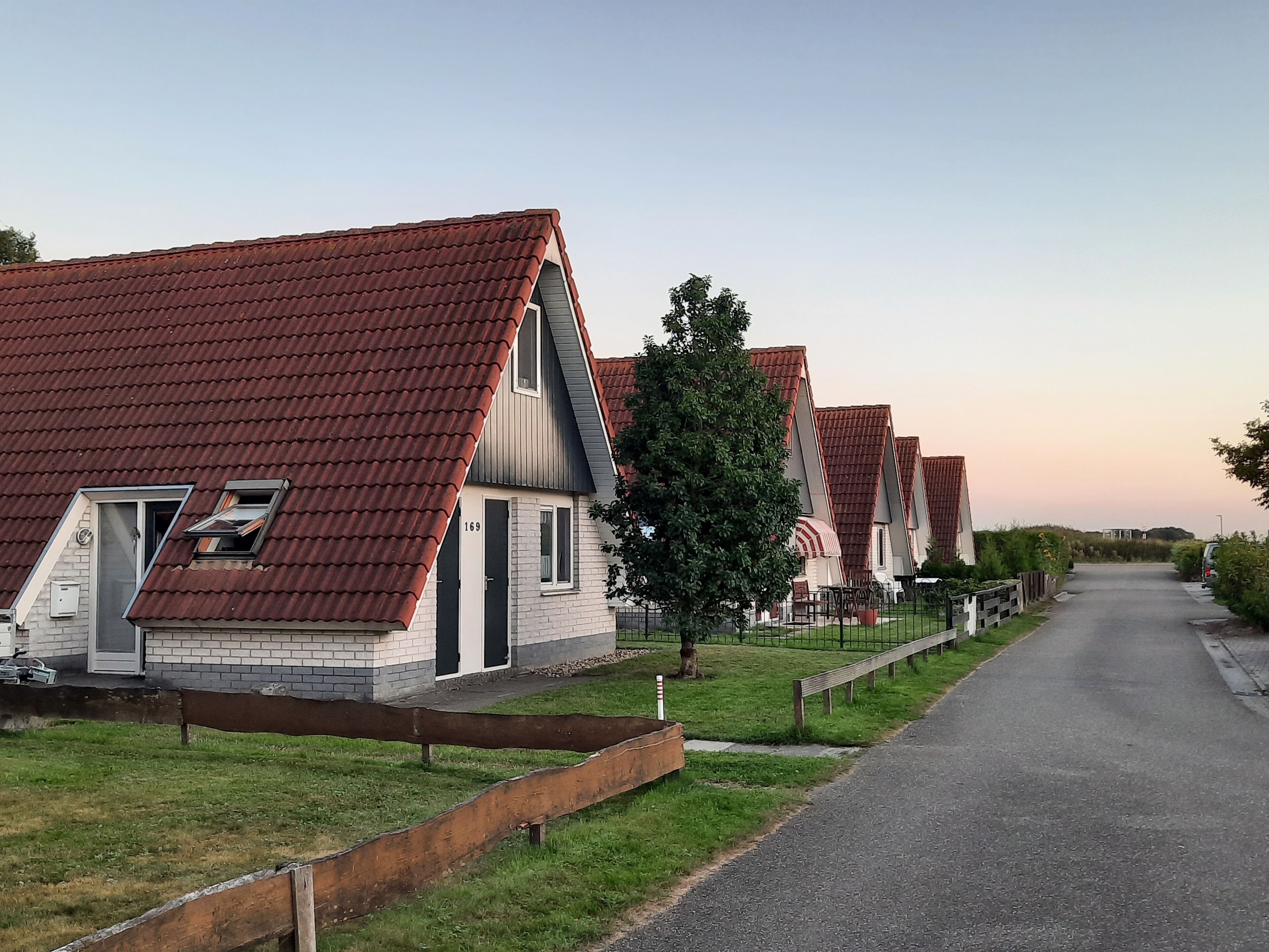 Een rij moderne huizen met schuine daken en een geplaveid pad.