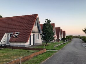 A row of modern houses with sloped roofs and a paved driveway.