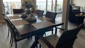 A dining area with a large table, wicker chairs, and a view of the water. - McDonald Manor at Cedar Creek Lake| Modern Lakefront Getaway (Gun Barrel City)