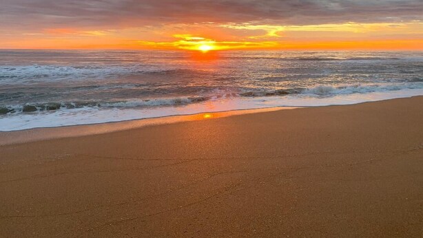 Een strand met een zonsondergang boven de oceaan.