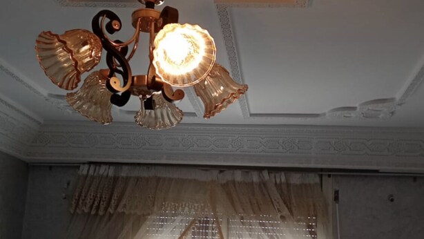 A room with a decorative ceiling, ornate curtains, and a patterned bedspread.