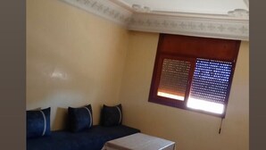 A living room with a sofa, a small table, and a window with blinds.