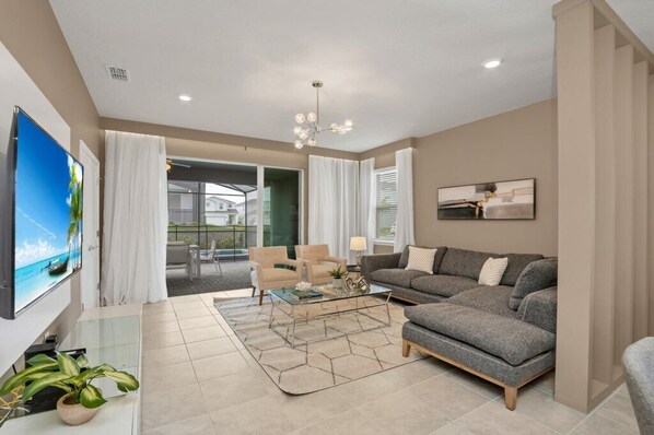 A modern living room with a sofa, armchairs, a coffee table, and a TV.