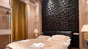Une chambre à coucher moderne avec un plafond au design géométrique, une tête de lit noire à texture et un plancher en bois.