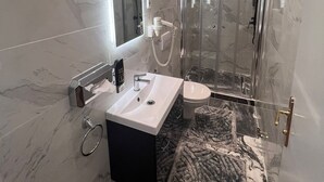 Une salle de bain moderne avec un meuble-lavabo en marbre, une cabine de douche en verre et un tapis à motifs de marbre.