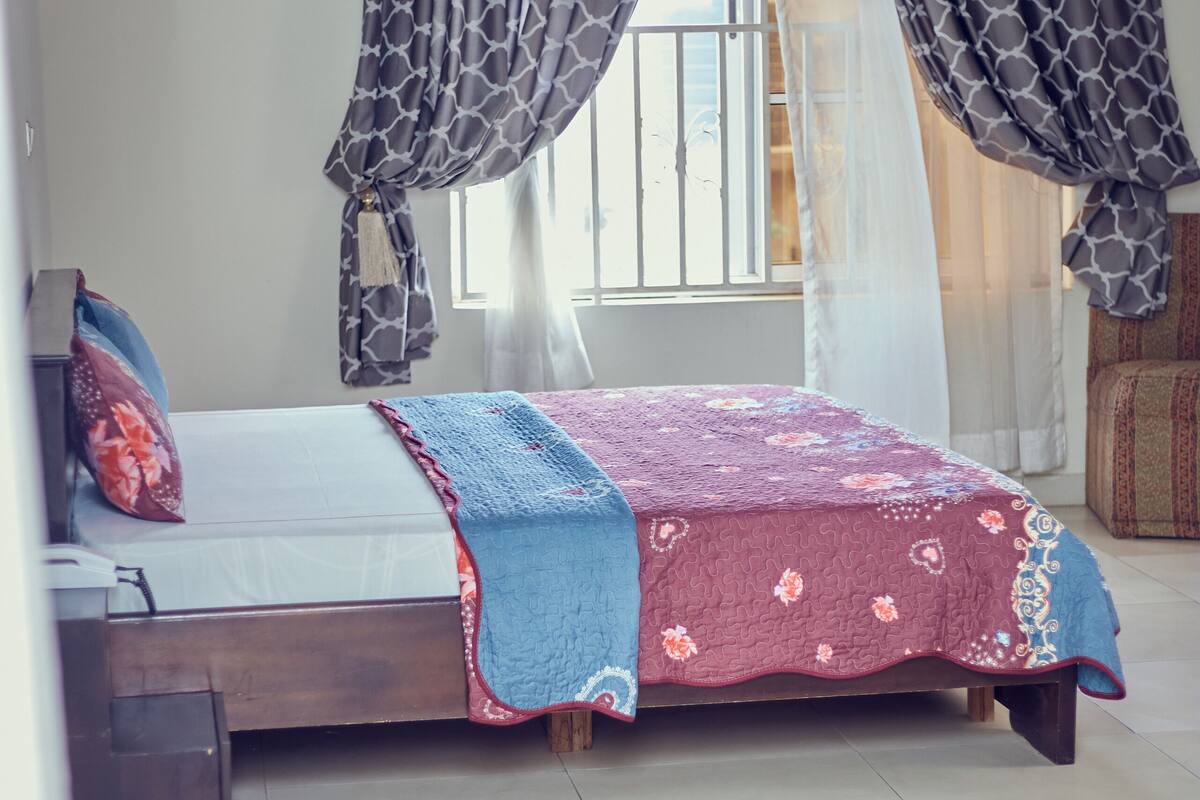 Een slaapkamer met een bed, gordijnen en een raam.