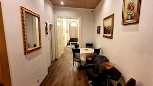 A narrow hallway with a dining area featuring a round table and chairs, a mirror, and framed pictures on the walls.