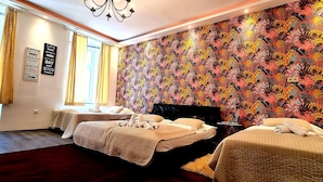 A hotel room with two beds, a large floral-patterned wall, and a window with curtains.