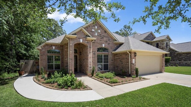 A two-story house with a brick facade, a garage, and a landscaped front yard. - Spacious Conroe Home < 4 miles to the Lake! (Montgomery)