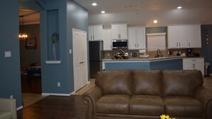 A modern kitchen with white cabinets, a brown leather sofa, and recessed ceiling lights. - Spacious Conroe Home < 4 miles to the Lake! (Montgomery)