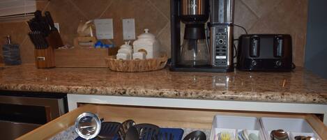 A kitchen counter with a coffee maker, toaster, and various utensils.