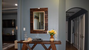 A hallway with a wooden console table, a mirror, and a vase with flowers. - Spacious Conroe Home < 4 miles to the Lake! (Montgomery)