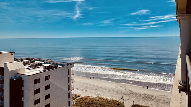 Un edificio alto con terraza en la azotea que da a una playa.
