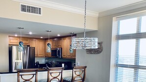 Una cocina moderna con armarios de madera, electrodomésticos de acero inoxidable y un comedor con mesa y sillas de vidrio.