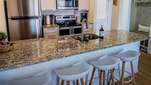 A modern kitchen with stainless steel appliances, a granite countertop, and bar stools. - Cozy Elk Hideaway - Walk to Ski Slopes!!! (Beech Mountain)