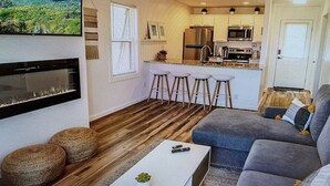A modern living room with a sofa, a coffee table, and a TV mounted on the wall. - Cozy Elk Hideaway - Walk to Ski Slopes!!! (Beech Mountain)