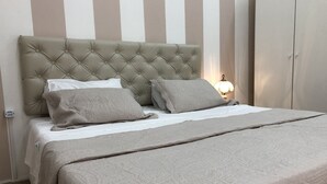 Una cama bien hecha con un cabecero capitonado, dos almohadas y una colcha estampada.