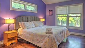 Ein Schlafzimmer mit einem Bett, Nachttischen und zwei Fenstern.