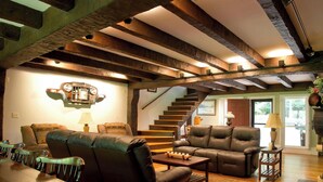 Un salón espacioso con una mesa de comedor de madera, sofás de cuero y una escalera que sube a otro nivel.