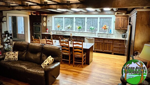 A cozy kitchen with a dining area, wooden cabinets, and a window with flowers.