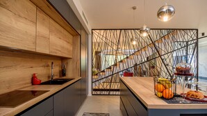 A modern kitchen with wooden cabinets, a black countertop, and a decorative metal partition. - Luxury Villa Cherry with indoor pool and outdoor jacuzzi (Marina)