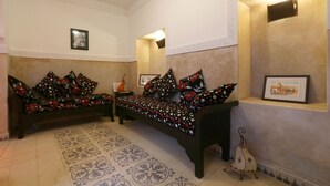 Un salon avec deux canapés, des coussins à motifs, un tapis décoratif et des tableaux encadrés accrochés aux murs.