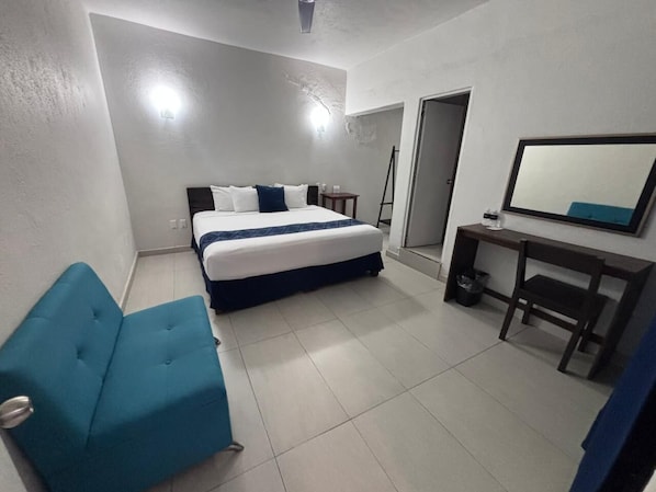 Un dormitorio con cama, escritorio, silla y sofá.