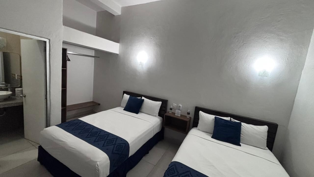 A hotel room with two beds, a bathroom, and a closet.