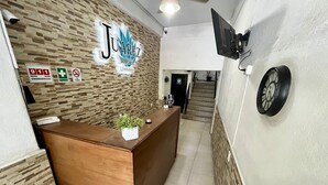 A hotel reception desk with a wooden counter, a potted plant, and a sign reading "Juarez Hotel". - Hotel Juarez 70 (Colima)