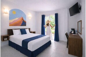 A hotel room with a bed, a desk, a TV, and a painting on the wall.