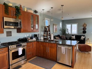 A modern kitchen with stainless steel appliances, wooden cabinets, and a central island. - Charming townhome, Pet Friendly, 5 Min to Downtown (Nashville)
