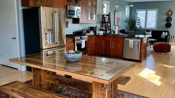 A modern kitchen with a central island, wooden cabinetry, and a large rug.