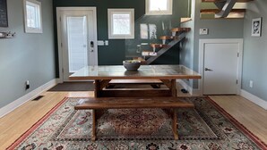 Un coin repas avec une table et un banc en bois, un tapis à motifs et un escalier avec des poutres en bois.