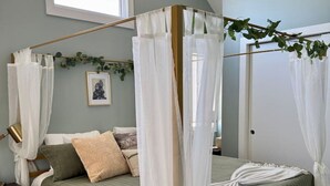 Une chambre à coucher avec une couvre-lit verte, un lit à baldaquin blanc et une petite table de chevet.
