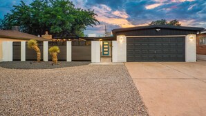A residential property with a garage, a driveway, and a landscaped area with cacti. - Uptown Area! Putting Green-BBQ-Hot Tub-Game Room (Albuquerque)