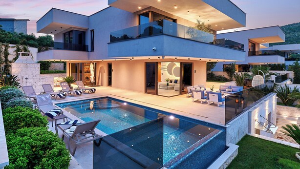 Ein modernes mehrstöckiges Haus mit Swimmingpool, Sitzgelegenheiten im Freien und einem gepflegten Garten.