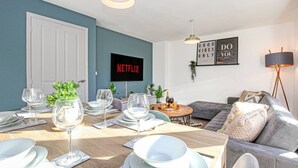 Una sala de estar moderna con comedor, televisor de pantalla plana y un sofá acogedor.