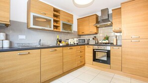 Una cocina moderna con armarios de madera, microondas integrado, estufa y pileta.