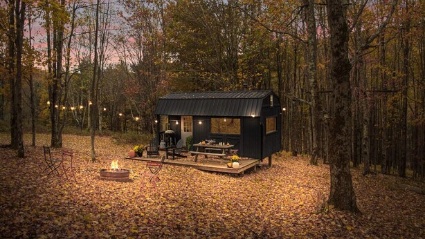 A cabin with a deck, a fire pit, and outdoor seating. - Off-Grid Tiny Cabin with Cozy Vintage Charm (Bovina)
