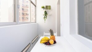 A bright, white room with a table set for breakfast, featuring a plate of fruit and a pineapple. - Home2Book Charming Center Apartment Santa Cruz (Santa Cruz de Tenerife)