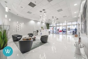 A modern lobby with a reception desk, seating area, and a glass entrance.