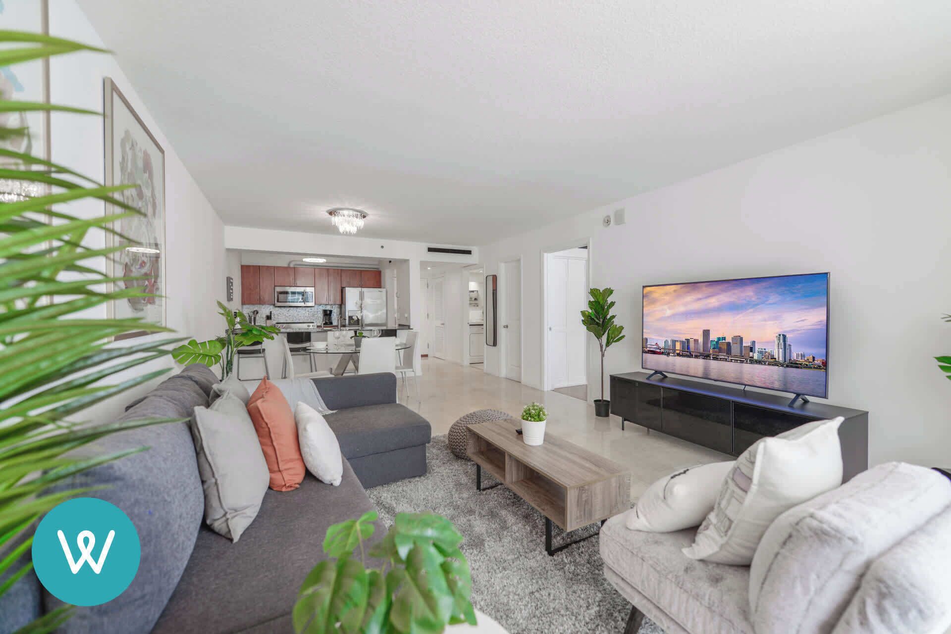 A modern living room with a grey sofa, a coffee table, and a TV displaying a cityscape.