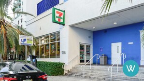 A 7-Eleven convenience store with a blue exterior and a parking sign indicating payment options. - Stylish 1BR | Free Parking | Near Kaseya Center (Miami)