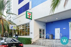 Un magasin de proximité 7-Eleven à la façade bleue, avec un panneau indiquant les options de paiement pour le stationnement.