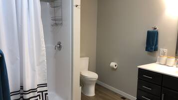 Un bagno con doccia, toilette e lavabo, con un asciugamano appeso al muro.
