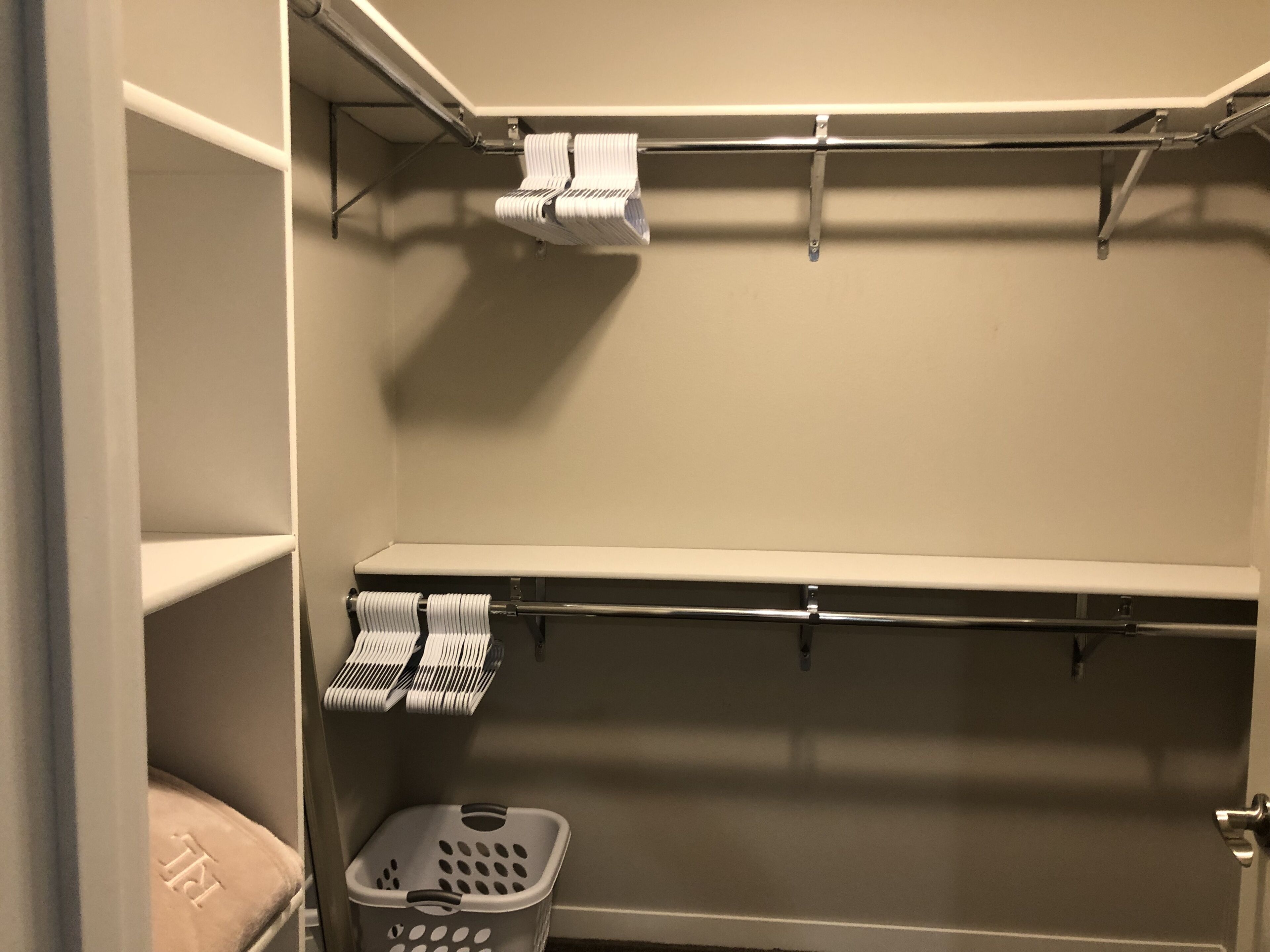 Un placard avec des étagères, une tringle pour suspendre les vêtements et un panier à linge.